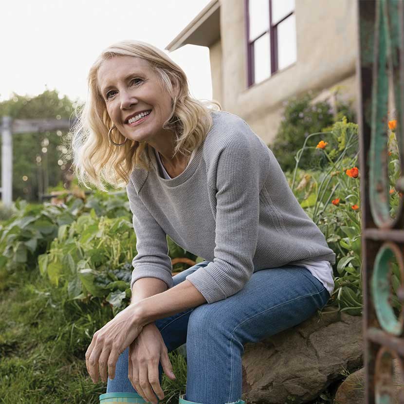 A woman rests outside her garden with peace of mind her retirement is better protected by TruStage™.