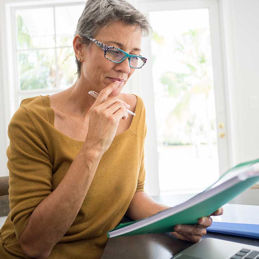 A woman seated at a desk checks a Behavioral Finance Advice report to help make more intentional investment choices.