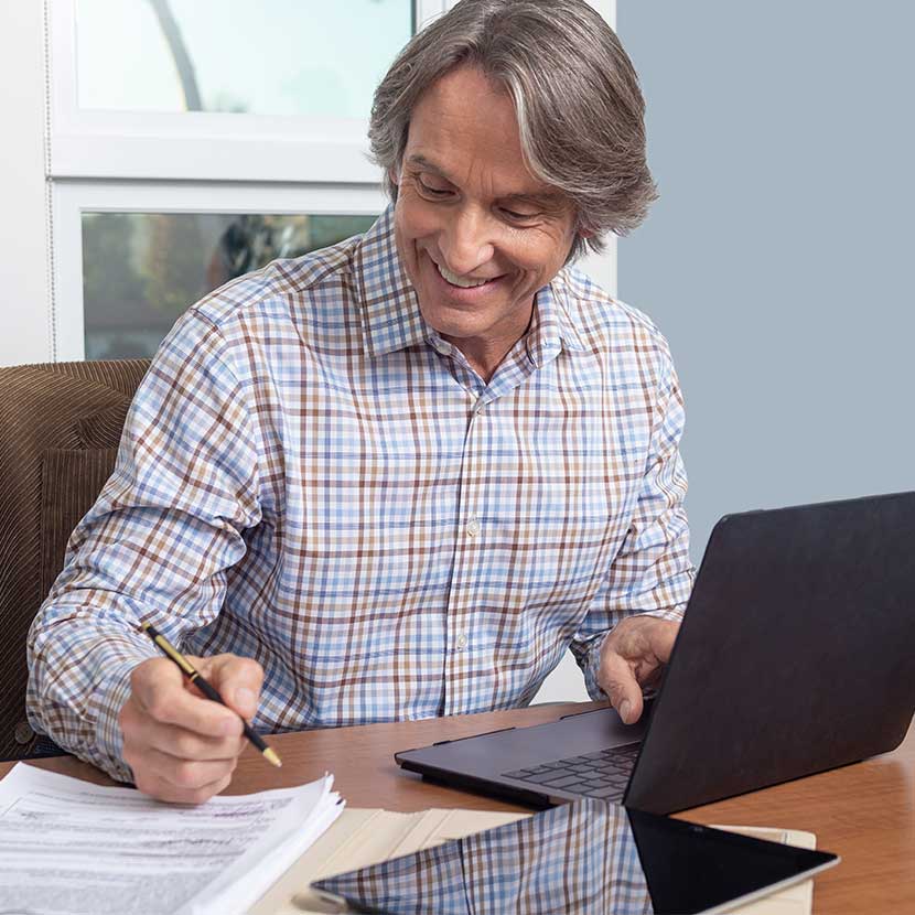 A man using a laptop checks his retirement portfolio's performance which includes a TruStage™ MaxProtect Fixed Annuity.