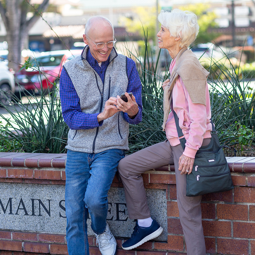 An older couple check their retirement portfolio via smartphone which includes a TruStage™ Zone Income RILA.