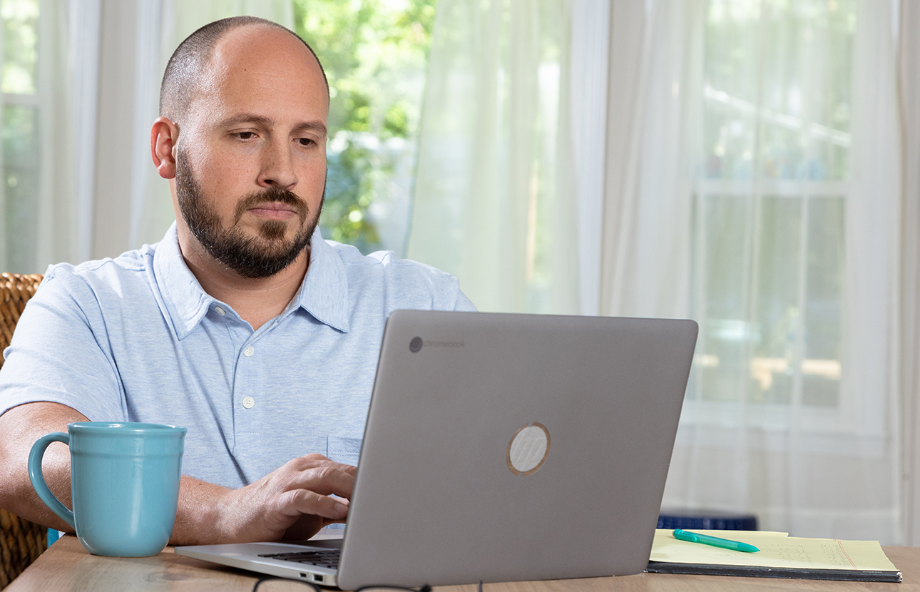 Man sitting at a desk, looking at his laptop