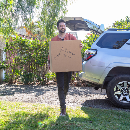 A man carrying a box into a house he has rented